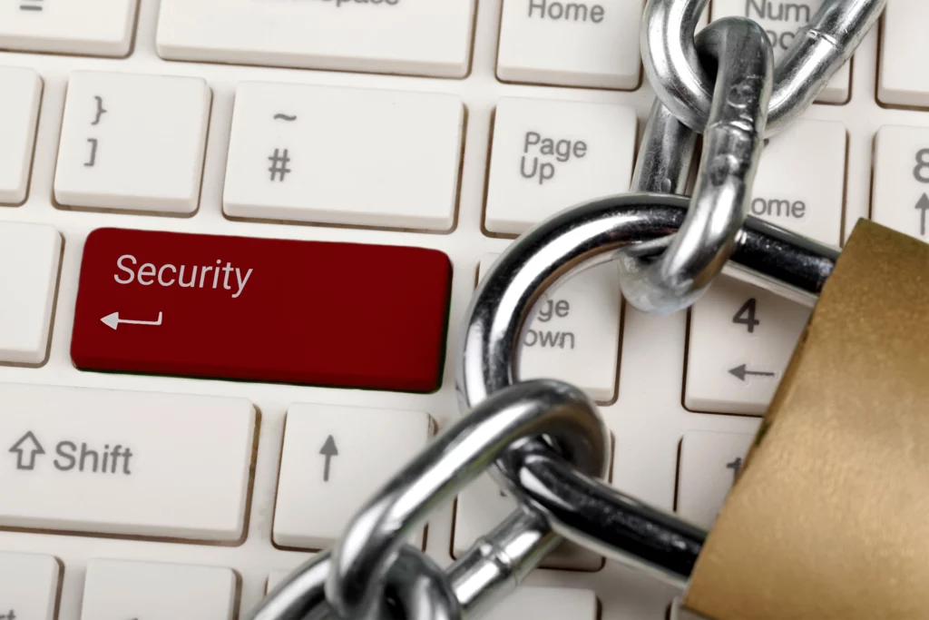 Rote Sicherheits-Taste auf einer Computer-Tastatur, umgeben von einer Kette und einem Schloss.