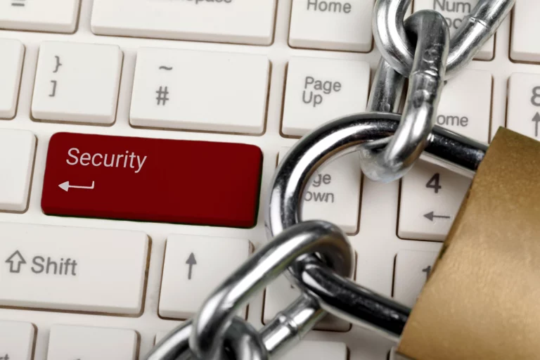 Rote Sicherheits-Taste auf einer Computer-Tastatur, umgeben von einer Kette und einem Schloss.