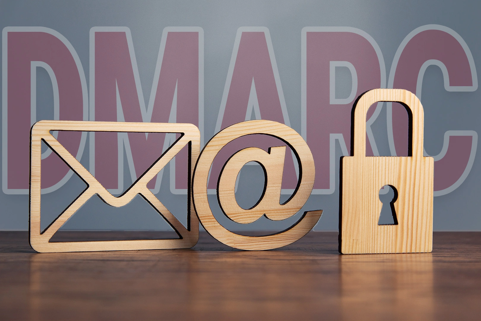 Holzbuchstaben und Symbole, die ein E-Mail-Symbol, ein @-Symbol und ein Vorhängeschloss darstellen und im Hintergrund liegt ein DMARC Schriftzug.